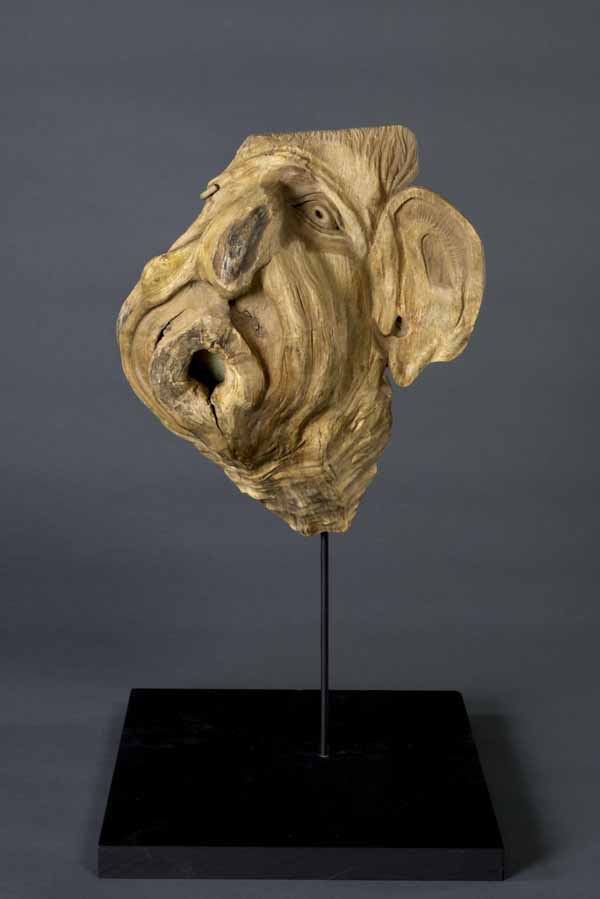 carving of a face wrinkling on itself to extremes from wind
