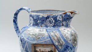 A large pearlware jug against a grey background with cobalt blue transferware designs.