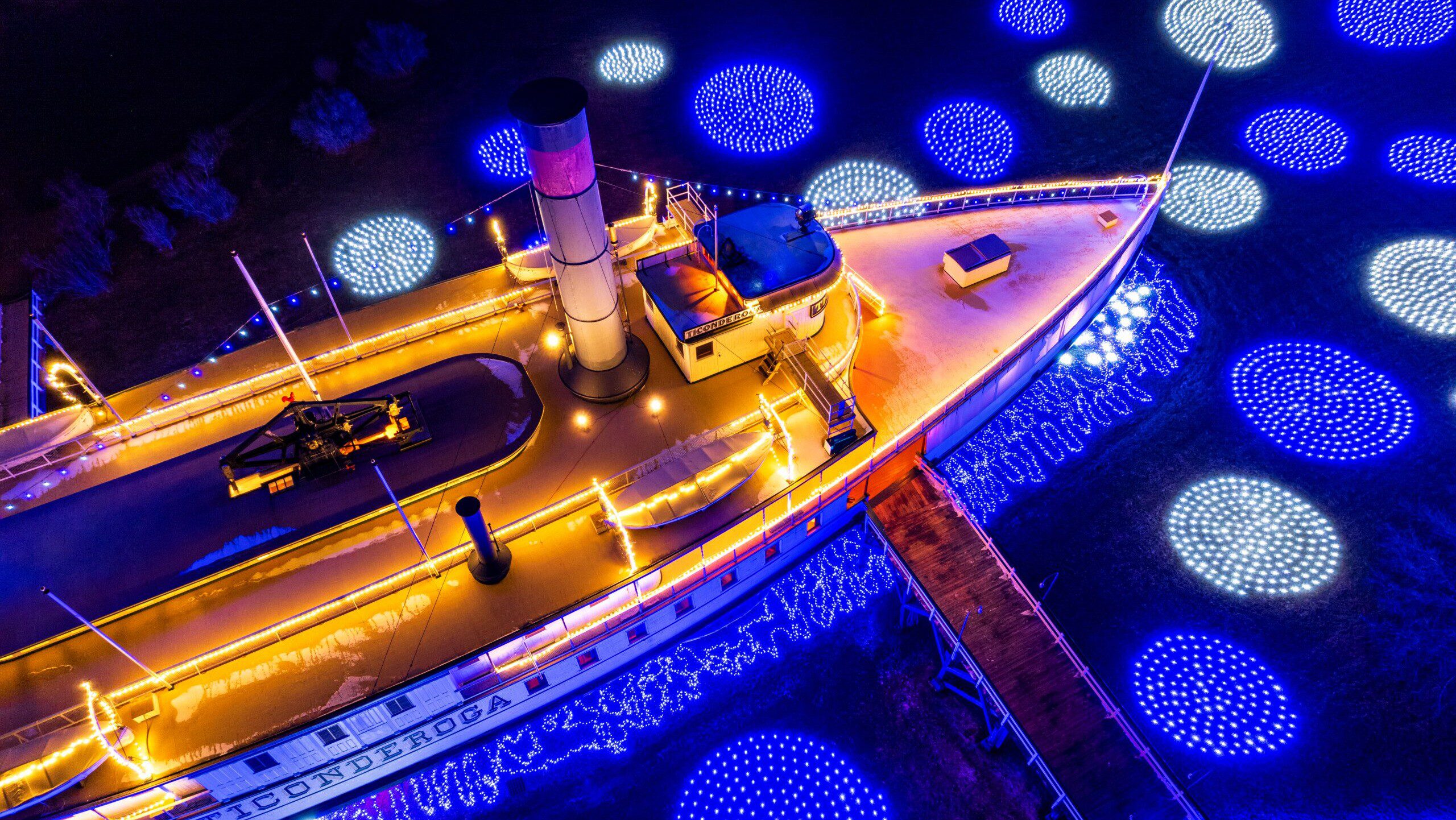 aerial view on the steamship Ticonderoga with blue circular lights arranged on the ground surrounding it.